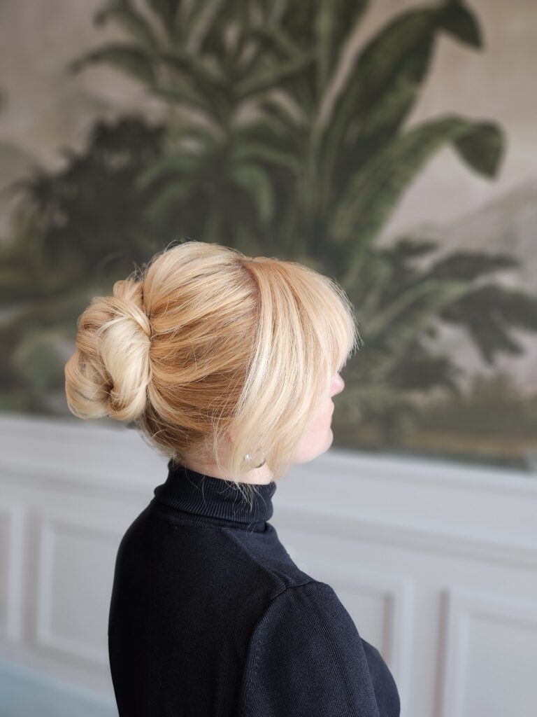 Fryzura weselna pełna blasku: gładki, klasyczny kok na zdrowych blond włosach, stylizacja i pielęgnacja wykonana przez specjalistów Maniewski.
