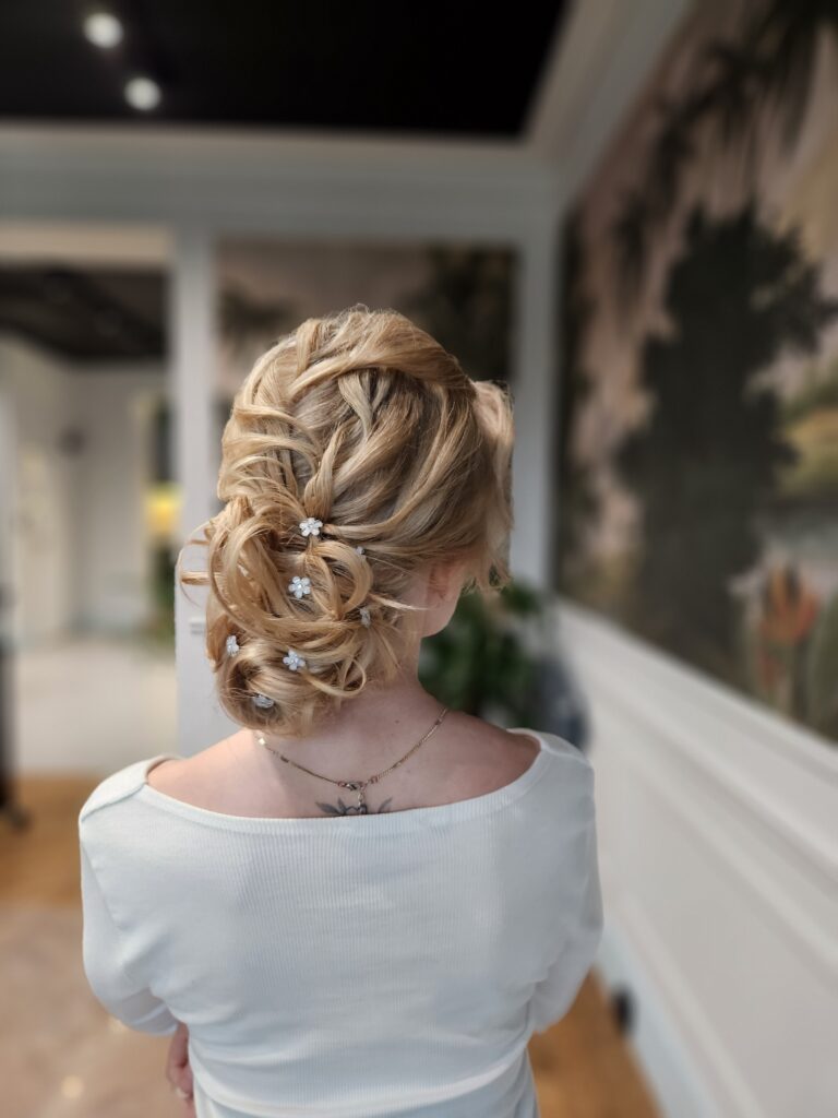 Teksturowane upięcie blond z delikatnymi kwiatami, idealna fryzura na wesele dla średnich włosów, stworzona przez ekspertów Maniewski.